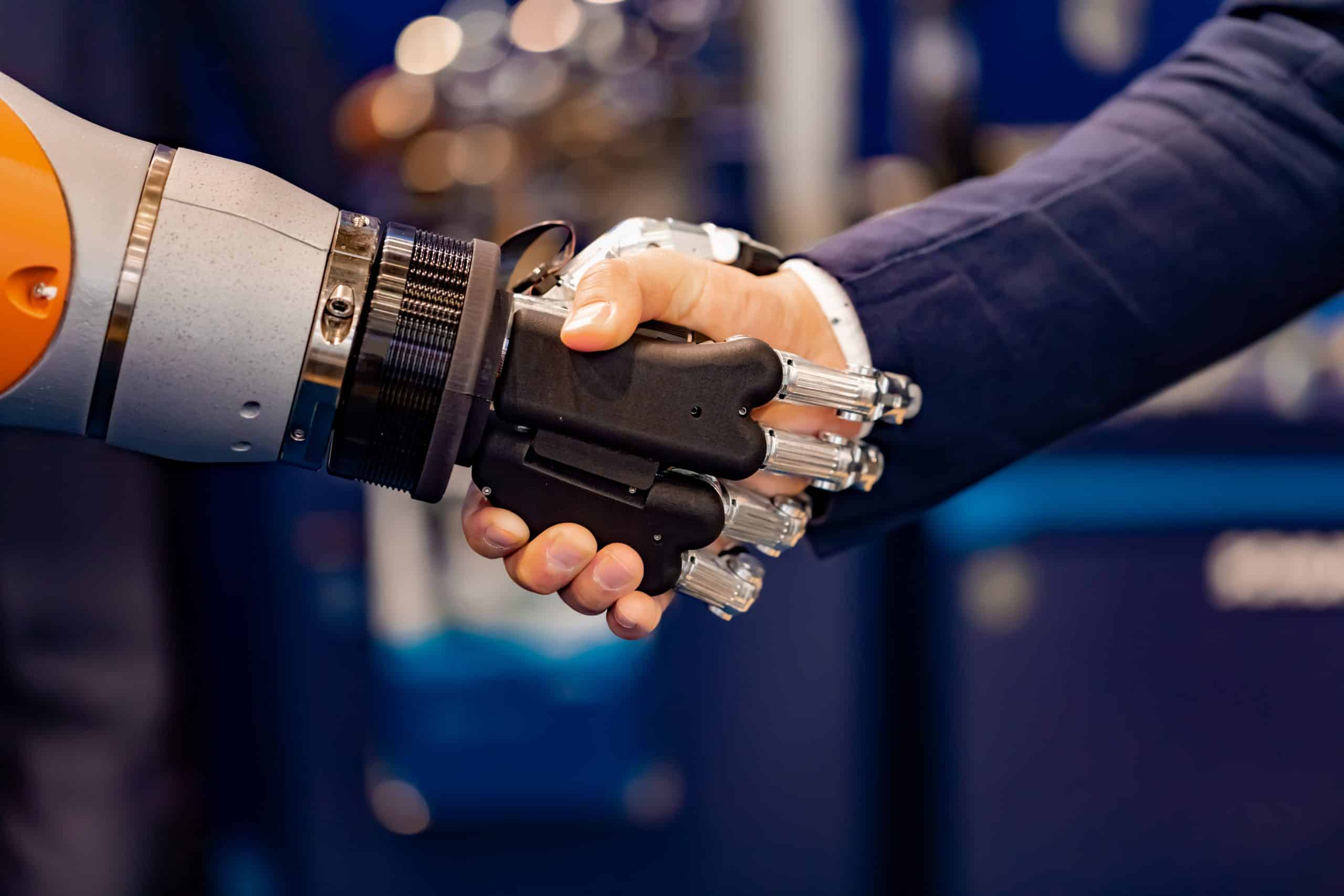 Hand of a businessman shaking hands with a Android robot. The concept of human interaction with artificial intelligence.